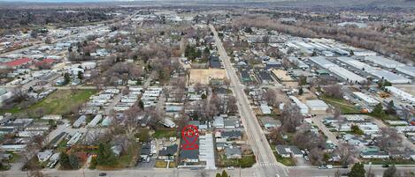 An aerial view of a residential area with multiple houses, a central road, and a large industrial building.