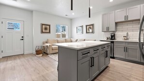 A modern kitchen with grey cabinets, a central island, and pendant lighting. - The *Minimalist's Escape* near Greenbelt & Winery with HOT TUB! (Garden City)