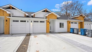 A residential garage with white doors, wooden accents, and a concrete driveway. - The *Minimalist's Escape* near Greenbelt & Winery with HOT TUB! (Garden City)
