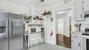 Una cocina moderna con refrigerador de acero inoxidable, área de café y alacenas blancas.