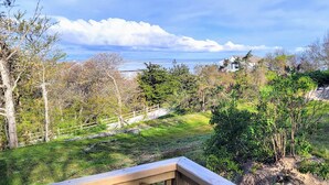 A coastal landscape with a wooden deck, a stone wall, and a view of the sea. - Private Beach.  Fabulous Bay Views. WIFI (Brewster)