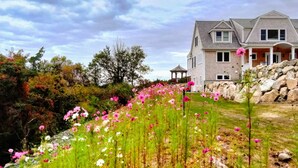 A house with a stone retaining wall and a garden with pink flowers. - Private Beach.  Fabulous Bay Views. WIFI (Brewster)