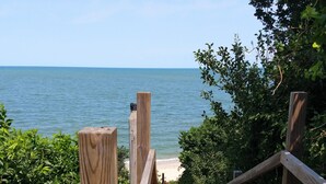 A wooden pathway leading to a beach, surrounded by greenery and flowers. - Private Beach.  Fabulous Bay Views. WIFI (Brewster)