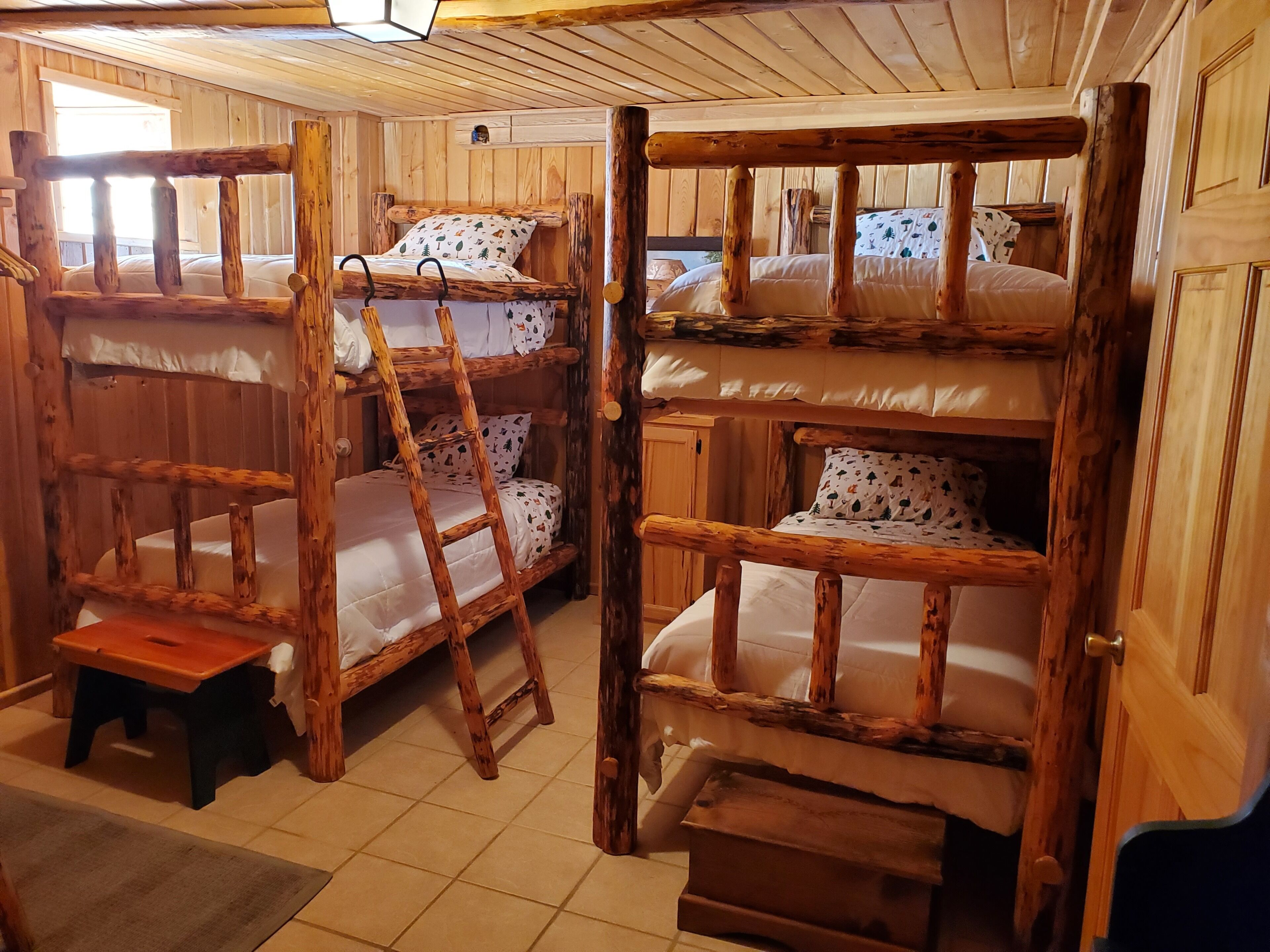 Una cabaña con literas, una escalera y un taburete pequeño.