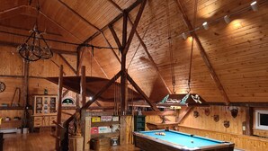 Ein Holzinterieur mit Billardtisch, Holzkabinetten und einem Schild, das einen Barbereich kennzeichnet.