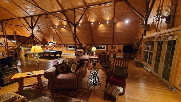 Ein geräumiger Loft mit hohen Decken, Holzbalken und einer gemütlichen Sitzecke mit Billardtisch.