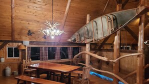 Ein rustikaler Holzraum mit Esstisch, Bänken, einer Kandelaber und einer ungewöhnlichen Rutsche.