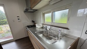 A modern kitchen with a stainless steel sink, wooden cabinets, and a window overlooking a garden.