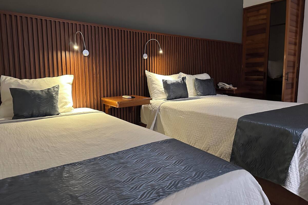 A hotel room with two beds, wooden paneling on the walls, and bedside lamps.