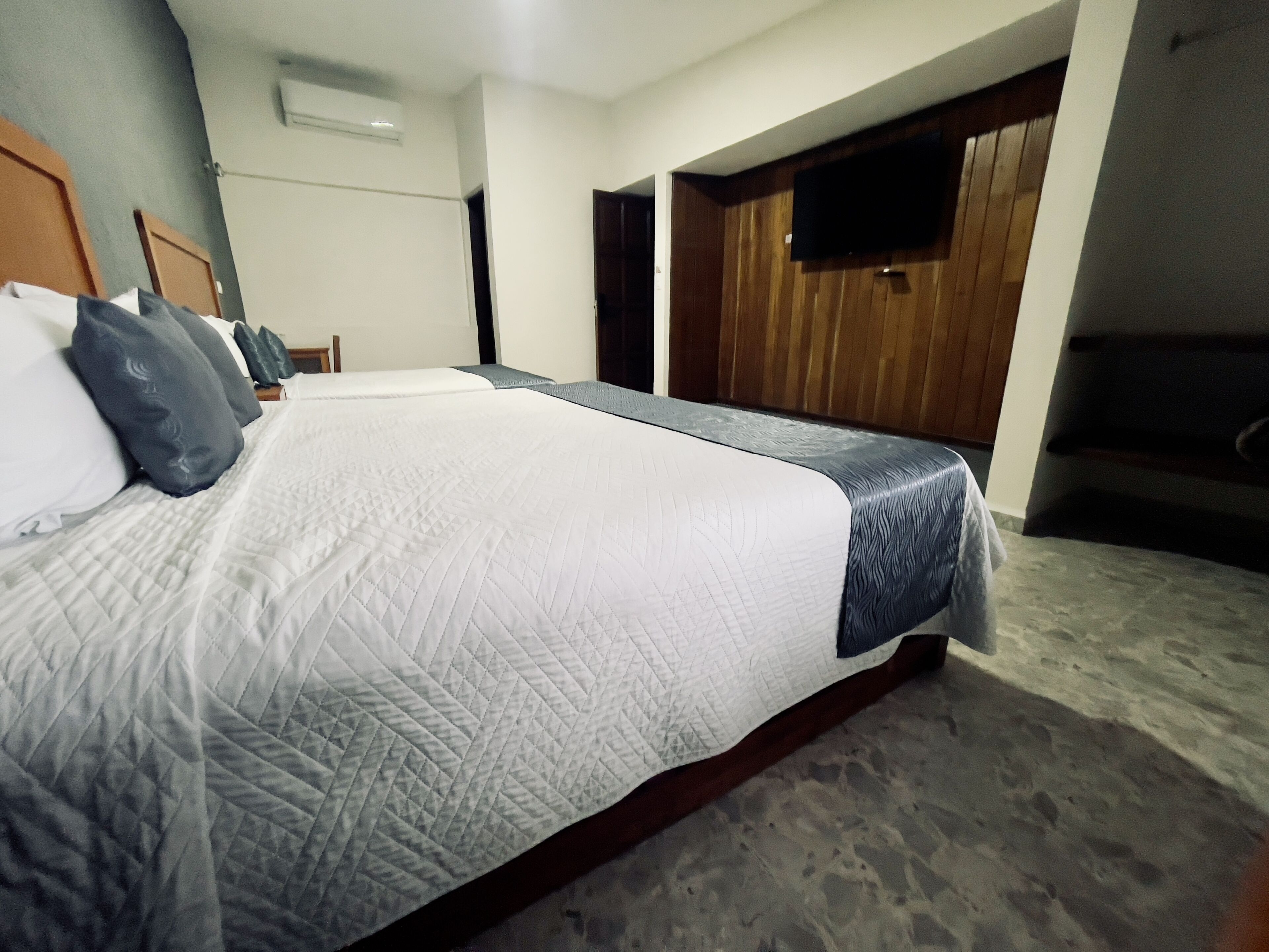 A hotel room with a large bed, a wooden wardrobe, and a flat-screen TV mounted on the wall.