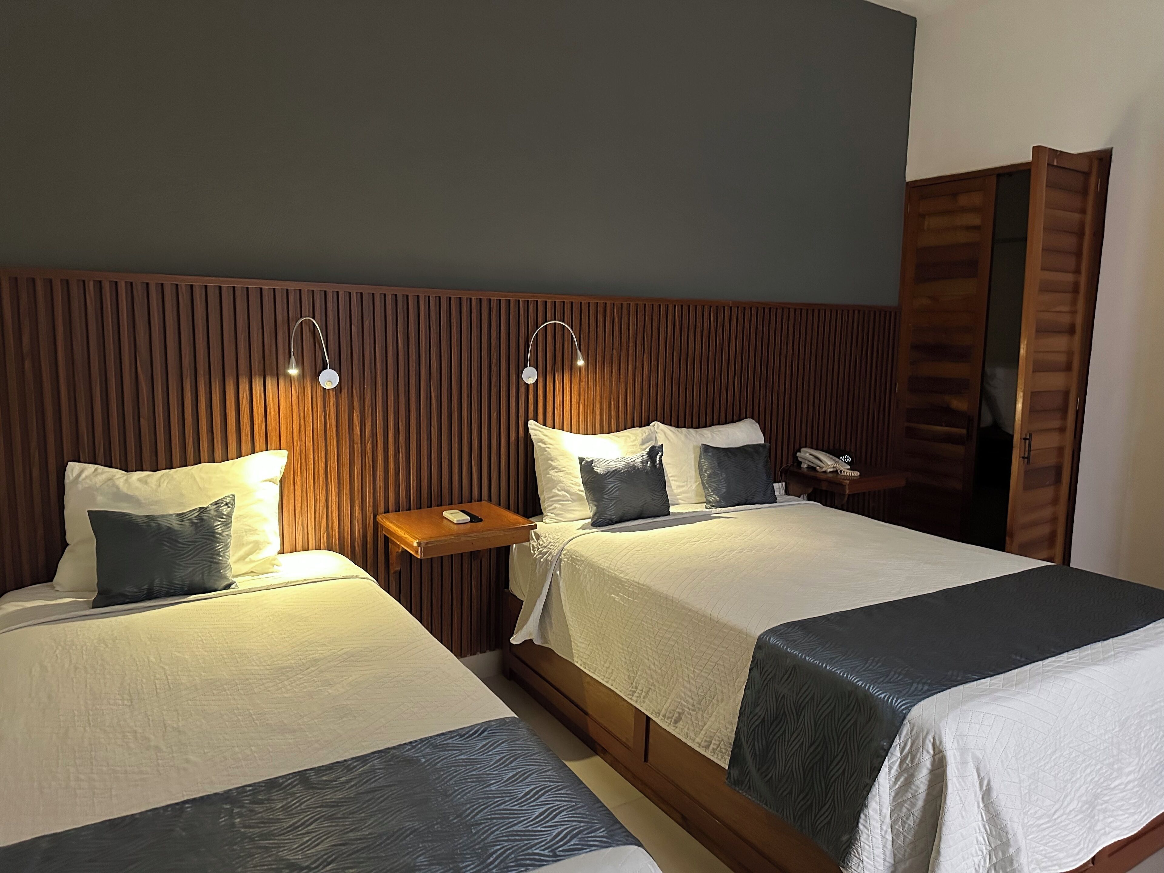 Two beds with headboards, bedside tables, and a wooden wardrobe.
