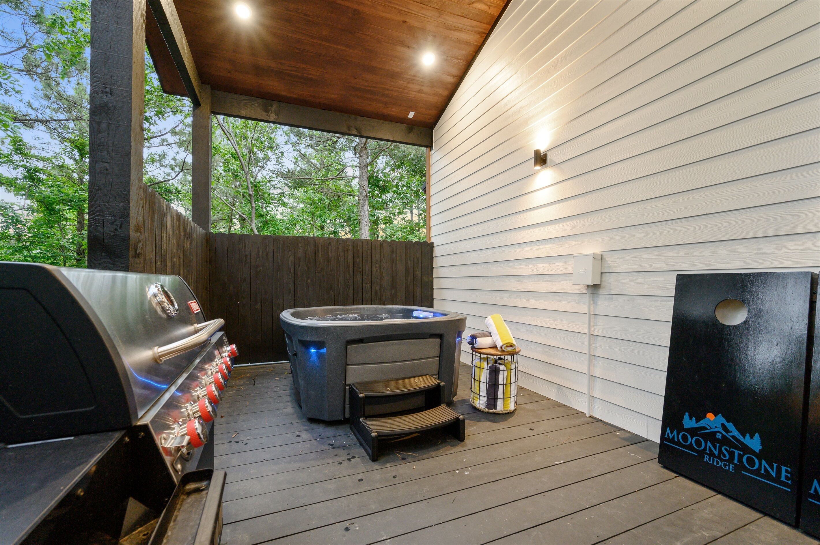 An outdoor deck with a barbecue grill, a hot tub, and a wooden fence.