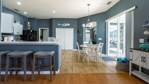 Una cocina moderna con una isla central, taburetes de bar y una zona de comedor con mesa y sillas.