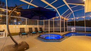 Un área de piscina exterior cubierta con jacuzzi, sillones de descanso y ventilador de techo.