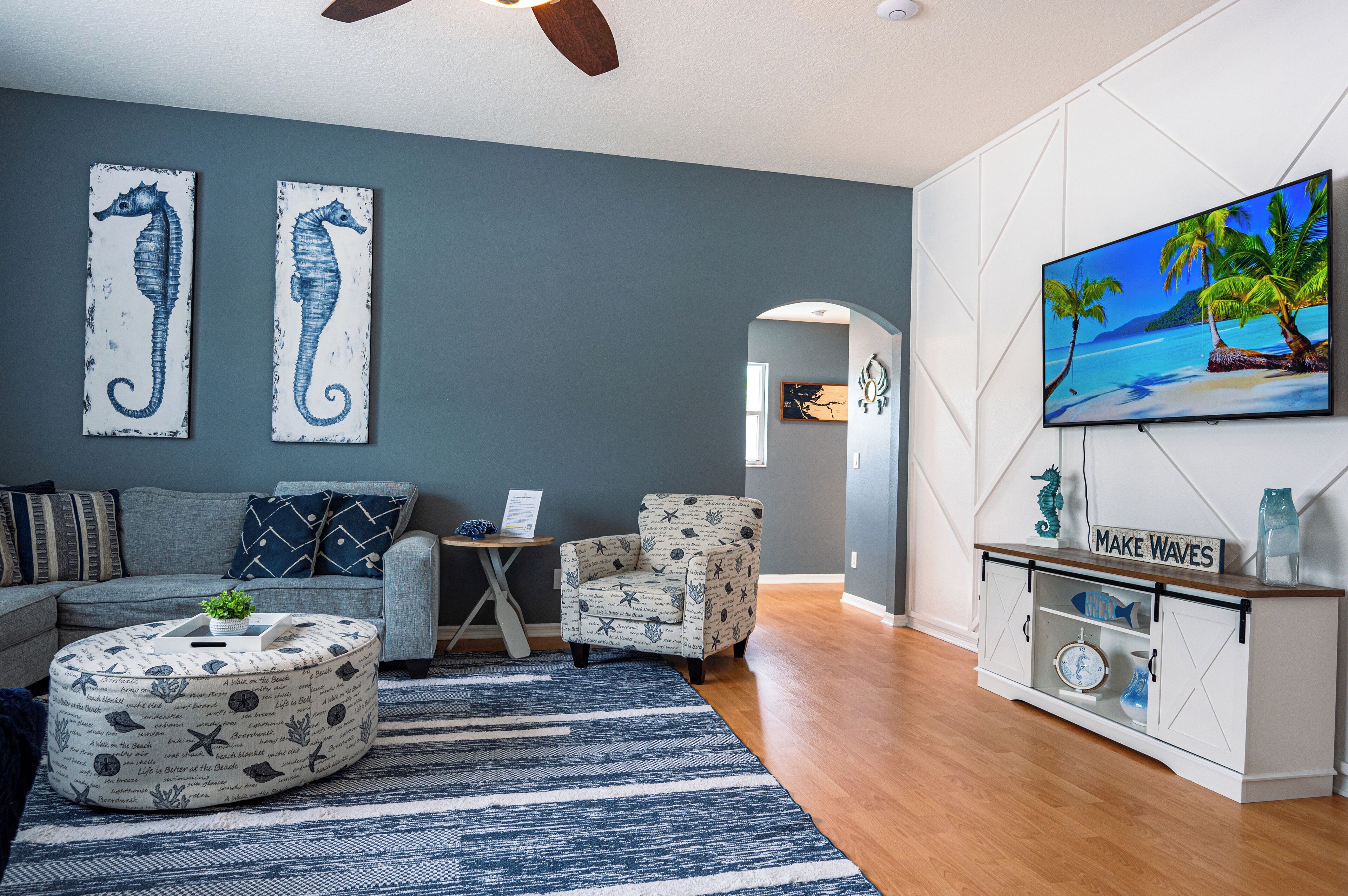 A living room with a grey wall, a sofa, a coffee table, a chair, a TV, and a cabinet.