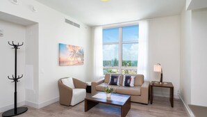 A modern living room with a sofa, armchair, coffee table, and a floor lamp. - Luxury Condo with Tranquil Water View-CS13 (Hollywood)