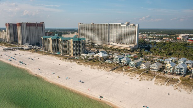 Un hotel frente a la playa con varias edificaciones, una playa de arena y una vista despejada del océano.