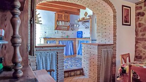 Una cocina rústica con paredes de ladrillo visto, techo de madera y suelo de baldosas.