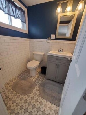 Une salle de bain avec des toilettes, un lavabo et un miroir.