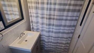A bathroom with a white sink, a mirror, a striped shower curtain, and a patterned floor.
