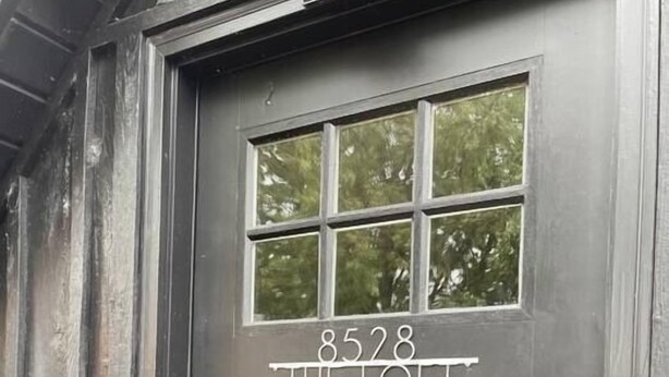Une porte en bois sombre, dotée d’une fenêtre et portant le numéro 8528.
