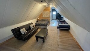 Une chambre mansardée chaleureuse, avec un lit en mezzanine, un canapé et une table basse.