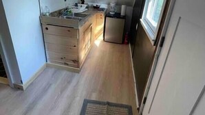 Une cuisine étroite, de plain-pied, avec un plan de travail en bois, un évier et un réfrigérateur.