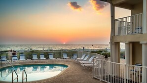 A pool area with lounge chairs and a view of the sunset over the ocean. - 🚤Belleair Beach Club #313 – Cozy Gulf-Front Condo with Stunning Views & Heated Pool!🩱 (Belleair Beach)