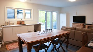 A modern kitchen with a wooden table and chairs, a built-in oven, and a large window.