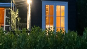 A house with a dark exterior, a visible window, and a porch area with a light fixture.