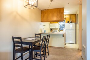 Una cocina compacta con armarios de madera, un refrigerador blanco y un comedor con mesa y sillas.