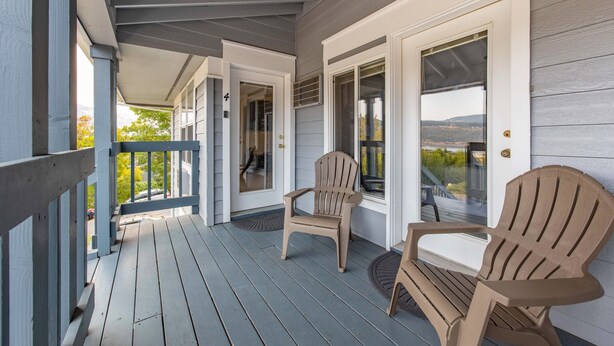 Un portico riparato con due poltrone Adirondack, un ponte di legno e vista sul paesaggio.