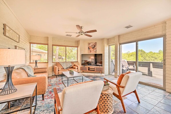 A spacious living room with a fireplace, comfortable seating, and large windows offering a view of the outdoors. - Patio & Panoramic Desert Views: Sedona Getaway! (Sedona)