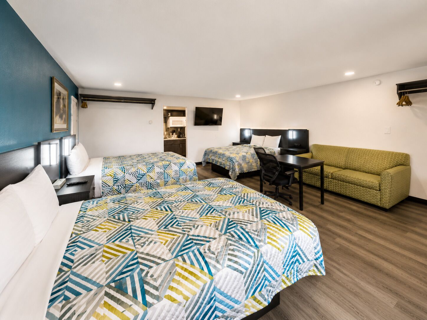 Une chambre d’hôtel avec un grand lit, un bureau, un canapé et un téléviseur fixé au mur.