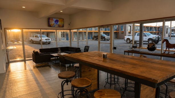 A modern bar area with a wooden bar, stools, and a sofa.