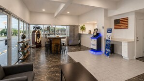 A modern lobby with a reception desk, bar area, seating, and a flag on the wall.