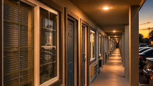 A corridor with doors and windows, leading to a parking area.
