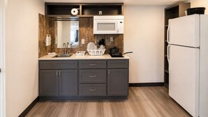A modern kitchen with a microwave, sink, cabinets, and a refrigerator.
