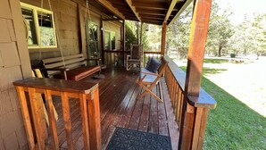 A wooden porch with a bench, a rocking chair, and a small table.