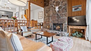A cozy living room with a stone fireplace, leather sofas, and a television. - RMR: Cinquefoil 1612 Condo in The Aspens/Wilson,WY (Wilson)