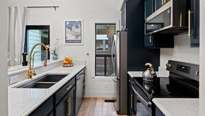 A modern kitchen with black cabinets, stainless steel appliances, and a marble countertop. - RMR: Cinquefoil 1612 Condo in The Aspens/Wilson,WY (Wilson)
