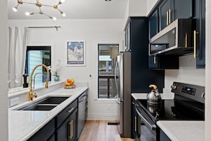 A modern kitchen with black cabinets, stainless steel appliances, and a marble countertop. - RMR: Cinquefoil 1612 Condo in The Aspens/Wilson,WY (Wilson)