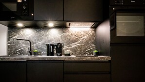 Ett modernt kök med en väggbeklädnad av marmor, en kaffemaskin och en mikrovågsugn.
