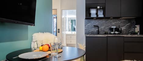 A modern kitchen with dark cabinets, a marble countertop, and a dining area with a round table set for two.