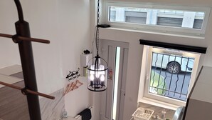 Et moderne køkken med en marmor bordplade, en hængende lampe og udsigt til gaden gennem et vindue.