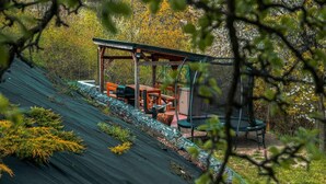 Un espace extérieur abrité avec une table et des chaises, un barbecue et une balançoire.