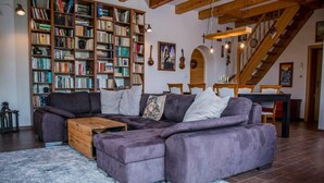 Un salon moderne avec un canapé d’angle, une table basse en bois et une grande bibliothèque remplie de livres.