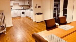 Une cuisine compacte avec des meubles blancs, un lave-linge et un coin repas comprenant une table et des chaises.