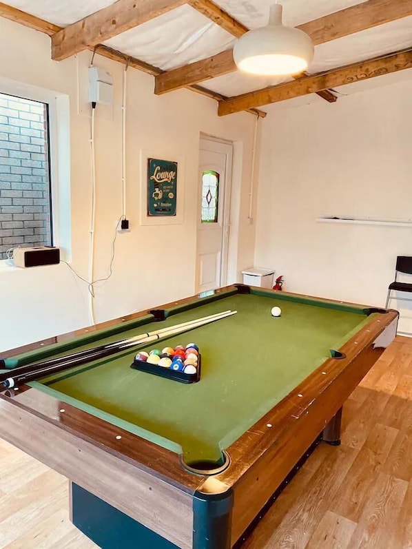 Una mesa de billar con bolas, una ventana con vistas y un letrero que dice 'Lounge'.
