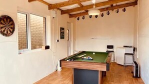 Une pièce équipée d’une table de billard, de cibles de fléchettes et d’une petite table avec des chaises.